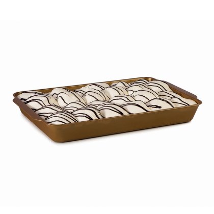 File di pasticcini glassati di bianco con linee di cioccolato fondente, in una teglia dorata rettangolare.