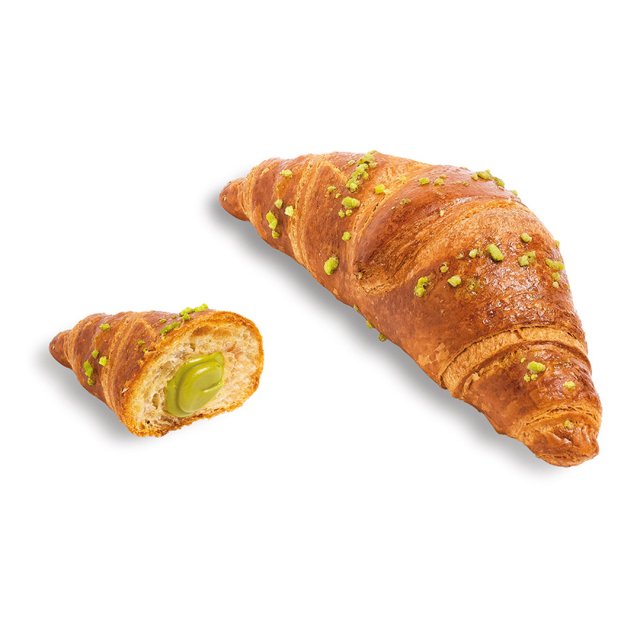 Croissant dorato con granella di pistacchio, una metà mostra un ripieno cremoso verde al pistacchio.