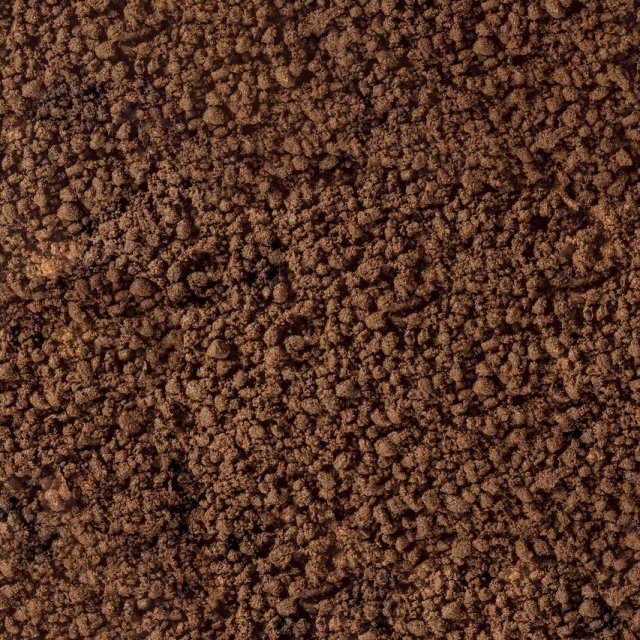 Primo piano di terra bruna sgranata o fondi di caffè dalla texture grezza e granulosa.