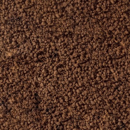 Primo piano di terra bruna sgranata o fondi di caffè dalla texture grezza e granulosa.