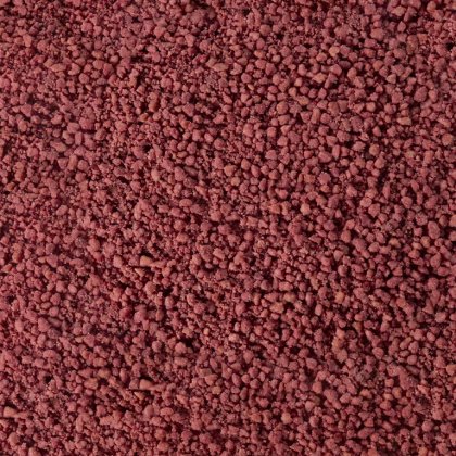 Texture ravvicinata di granuli o polvere grezza bruno-rossastra, simile a grani minerali o spezie agglomerate