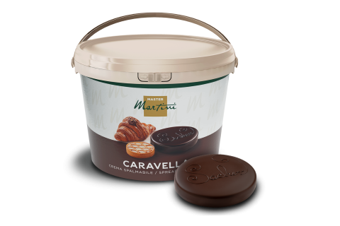 Secchio bianco di crema spalmabile Master Martini Caravella accanto a un disco di cioccolato fondente con decoro in r...