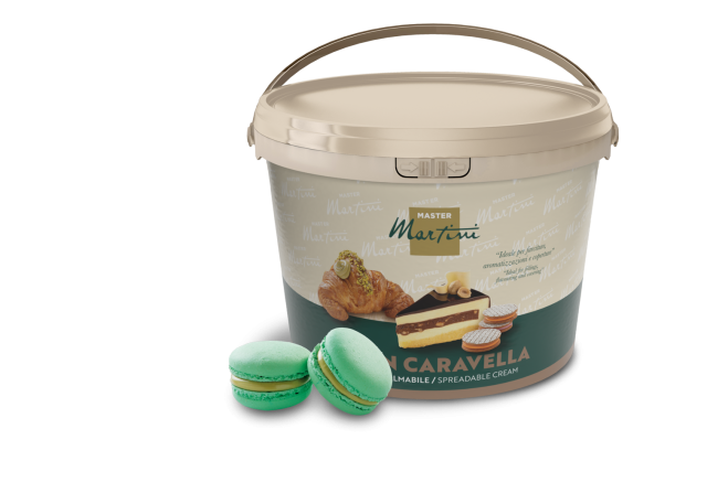 Vaschetta beige di crema spalmabile Master Martini con immagini di dolci, accanto a due macaron al pistacchio verdi.