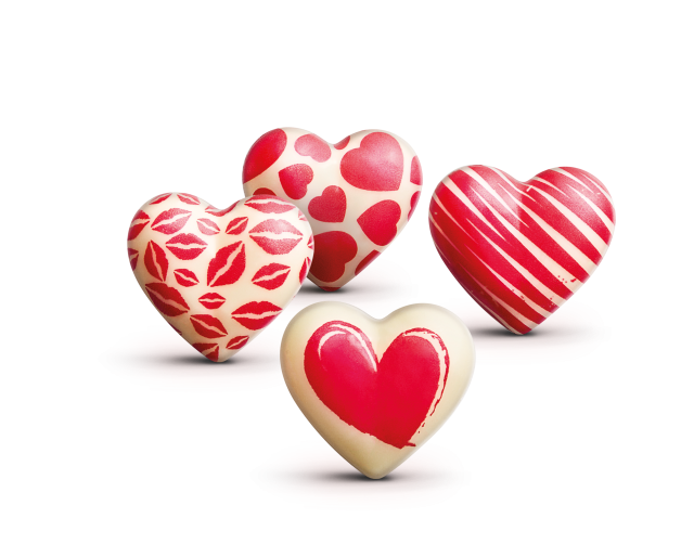 Quattro cioccolatini bianchi a forma di cuore decorati con labbra rosse, cuori, righe e motivo a cuore dipinto.