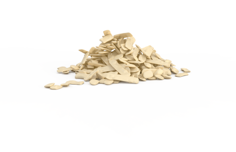 Mucchio di scaglie beige irregolari, simili a plastica o cera, su sfondo bianco.