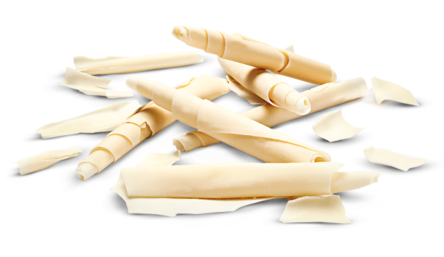 Riccioli di cioccolato bianco e pezzi a forma di riccio sparsi su sfondo bianco.