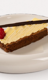Fetta di torta al cioccolato con crema, lampone e stecca di cioccolato su piatto bianco.