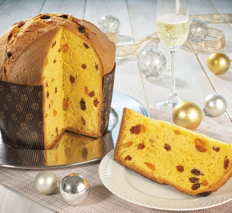 Panettone tradizionale italiano con una fetta tagliata, servito su un piatto con champagne e decorazioni dorate