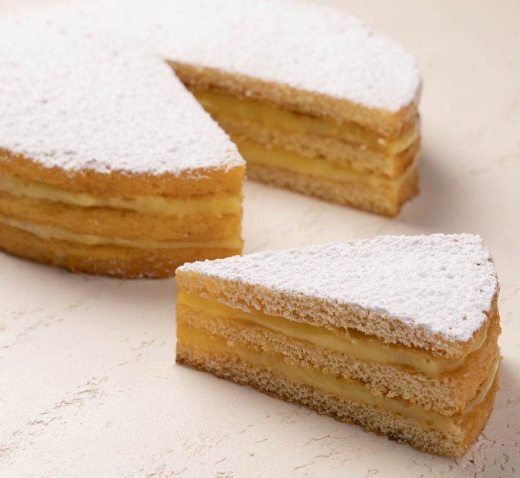 Torta rotonda a strati con crema, spolverata di zucchero a velo, con una fetta tagliata a fianco.
