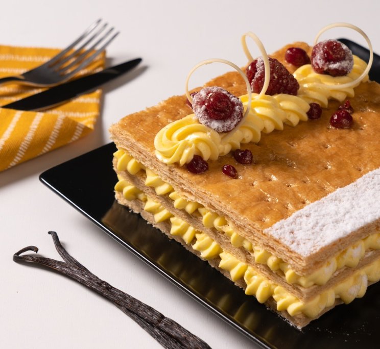 Millefoglie con crema alla vaniglia, lamponi freschi e mirtilli rossi zuccherati, su piatto nero