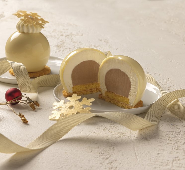 Dolce a cupola intero e a fette in cioccolato bianco, con crema a strati, decorato con nastro dorato