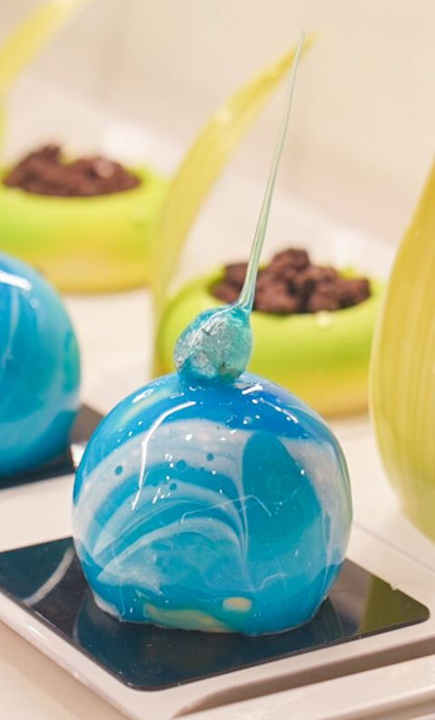 Sfere dessert marmorizzate blu lucide, coppette verdi con crumble al cioccolato e riccioli di zucchero
